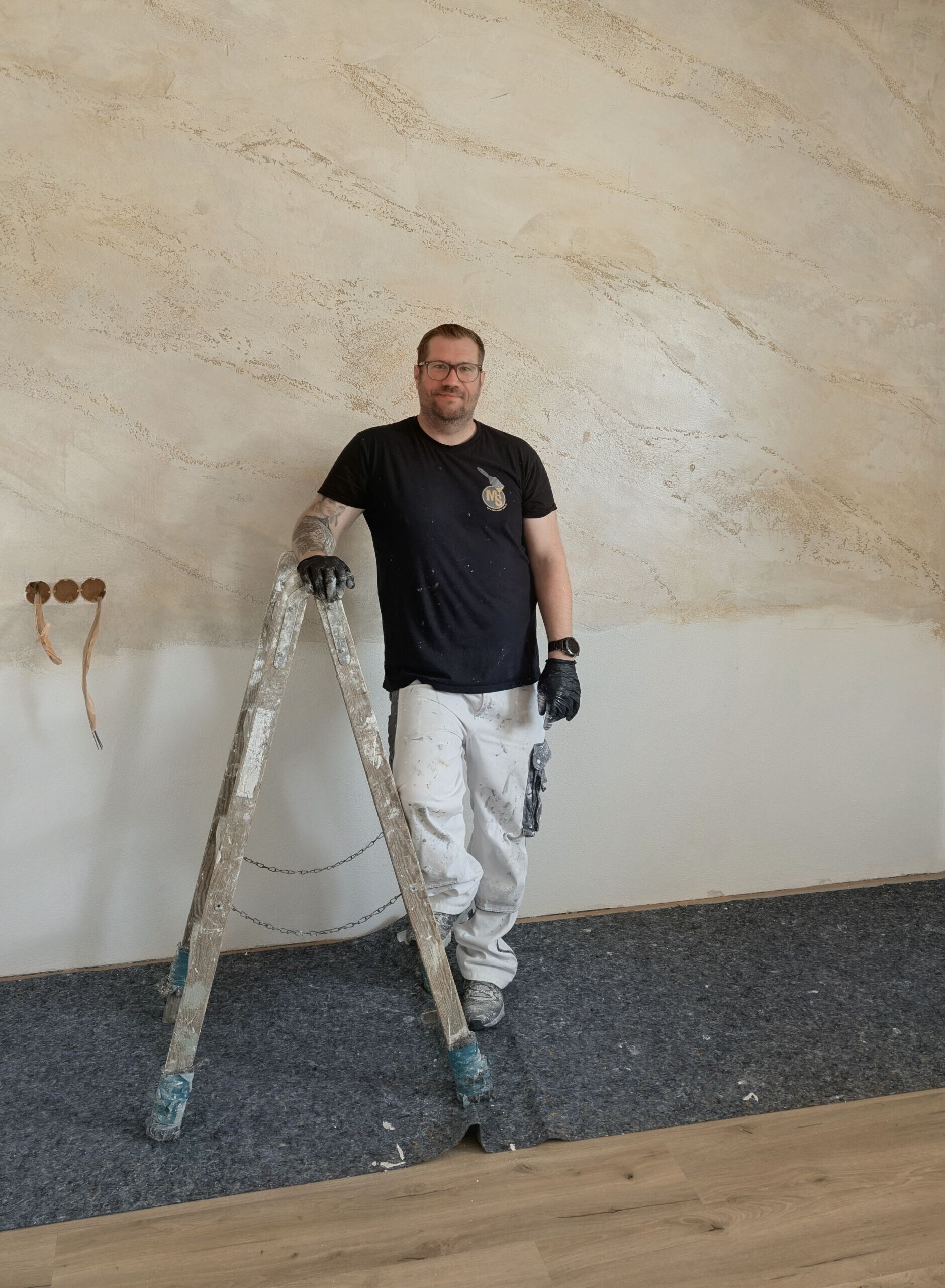 Malermeister Matthias Sinner vor einer Wand mit Spachteltechnik in Füssen