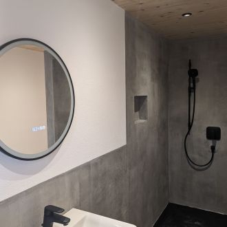 Fugenloses Bad in Betonoptik mit Dusche und rundem Spiegel – Referenz Malermeister Sinner