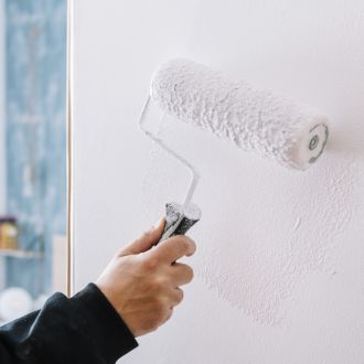 Maler streicht eine Wand mit der Farbrolle weiß